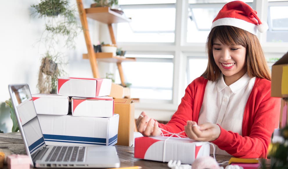 aktionslogistik und salespromotion Frau in Weihnachtsmannkostüm beim Verpacken eines Paketes für Aktionslogistik und Salespromotion